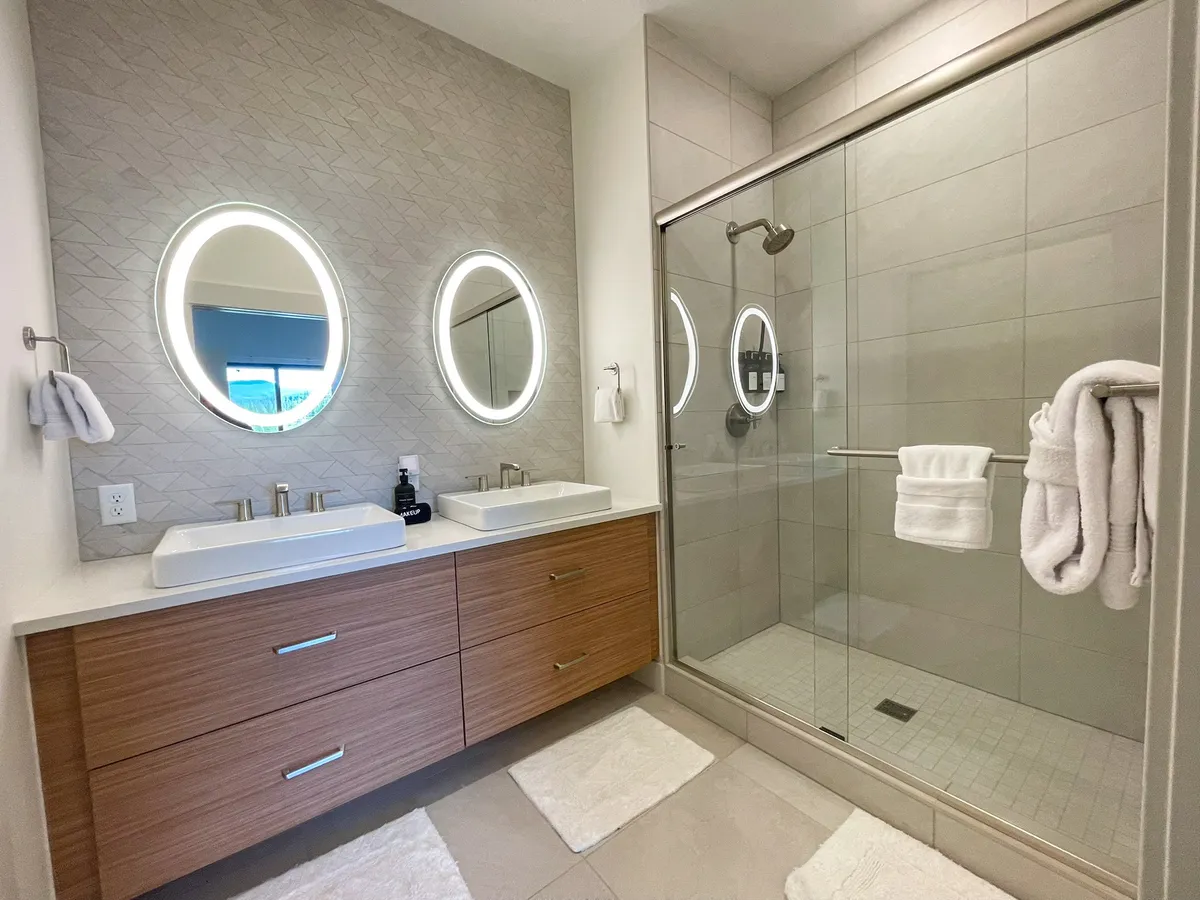 A spa-like bathroom with double vanity sinks, framed mirrors, and a walk-in glass shower. Clean lines and modern fixtures create a refreshing, luxurious atmosphere.