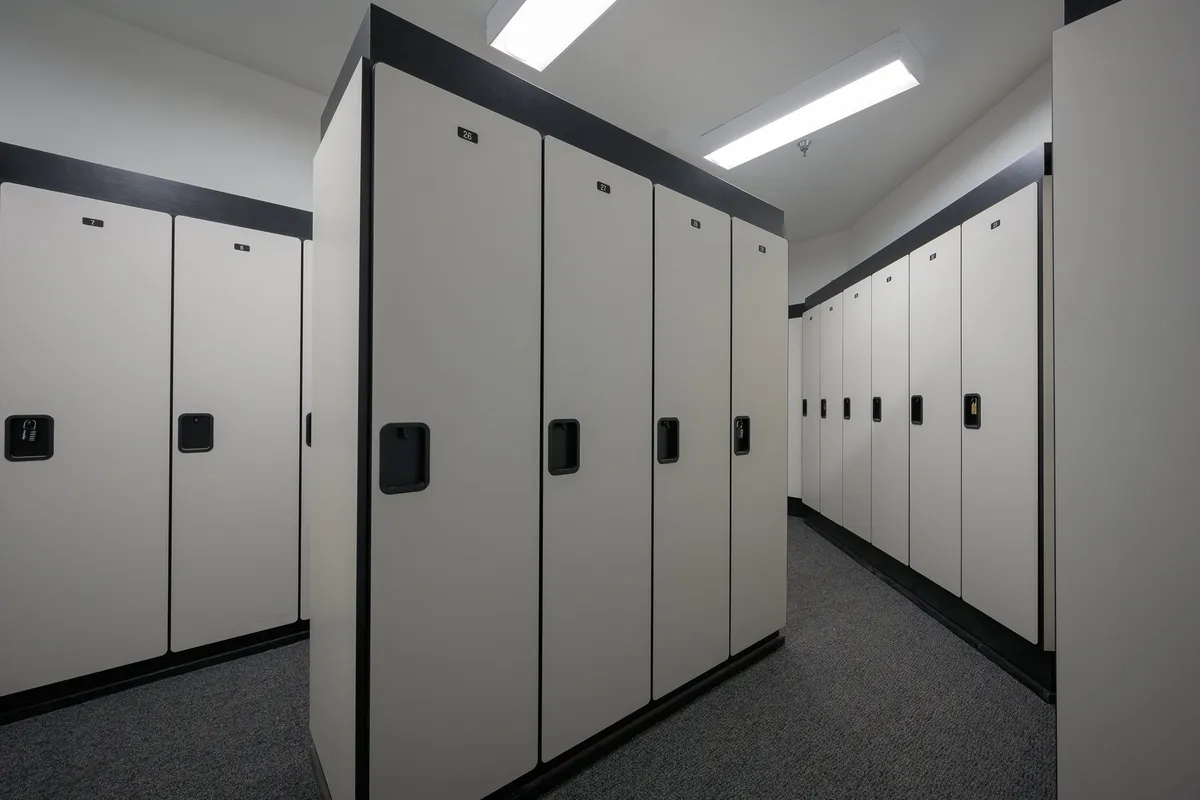 A row of clean, modern locking storage units lines a bright hallway, providing organized and secure spaces for storing gear. The simple color scheme and uncluttered design emphasize ease of use and efficiency, making it ideal for preparing for outdoor activities or stowing equipment after an adventure.